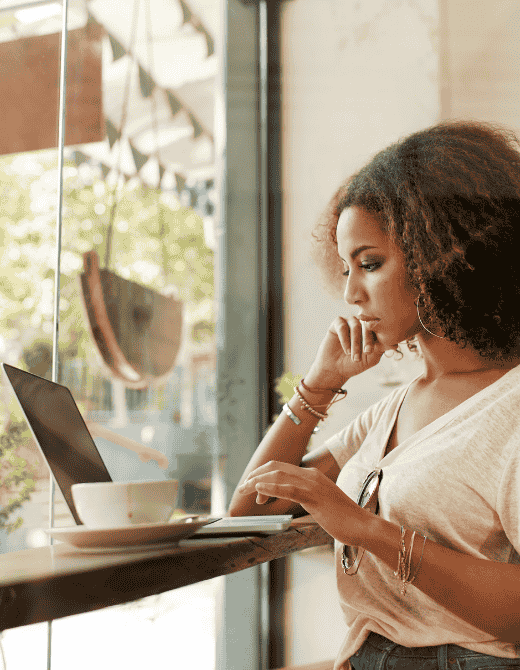 a woman sitting on her laptop at a cafe enjoying the business wifi